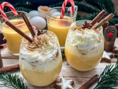 Festliche Gläser mit cremigem Eggnog, garniert mit Zimtstangen und Schlagsahne. Das perfekte Eggnog Rezept original für Weihnachten.