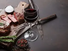 Ein saftiges Steak, perfekt zubereitet, mit einem Glas Rotwein. Was ist Malbec? Ein vollmundiger Wein, der dieses Gericht abrundet.