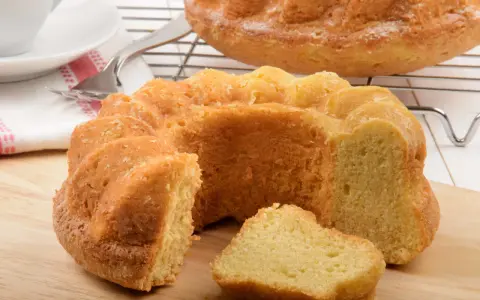 Ein goldbrauner Paradiescreme Kuchen, frisch gebacken und mit einem Stück abgetrennt, wartet auf Genuss.