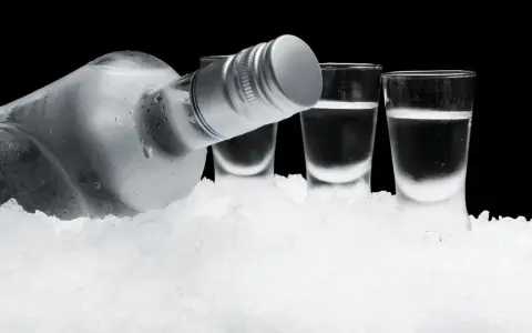 Eiskalte Flasche Wodka und drei Shotgläser auf Eis. So schmeckt Wodka am besten: rein und erfrischend.