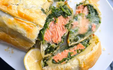 Saftiger Lachs mit Spinat in Blätterteig, ein köstliches Gericht für Fisch-Rezepte. Dazu eine Zitronenspalte.
