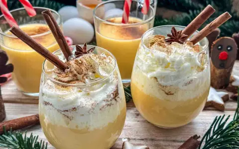 Festliche Gläser mit cremigem Eggnog, garniert mit Zimtstangen und Schlagsahne. Das perfekte Eggnog Rezept original für Weihnachten.