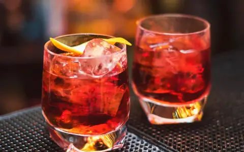 Zwei klassische Negroni-Cocktails mit Eis und Orangenzeste. Das perfekte Rezept für einen originalen Negroni.