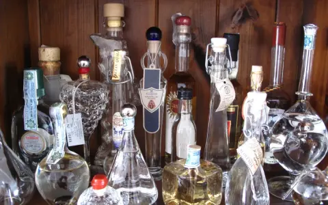 Regal voller Grappa-Flaschen, einige mit Etiketten, die den **Grappa Prozent** angeben.