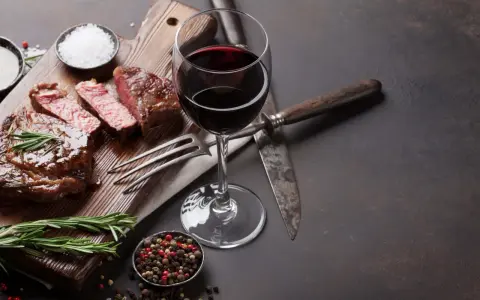 Ein saftiges Steak, perfekt zubereitet, mit einem Glas Rotwein. Was ist Malbec? Ein vollmundiger Wein, der dieses Gericht abrundet.