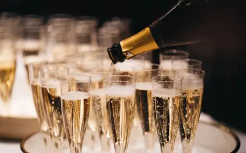 Sekt wird in Gläser gefüllt, die auf einem Tablett stehen. Die Bläschen steigen auf und erinnern daran, woher Champagner kommt.