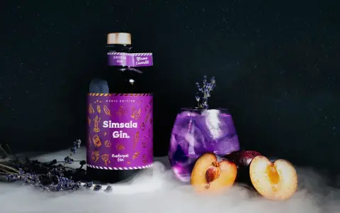 Ein magischer lila Gin Tonic mit Pflaume und Lavendel, daneben eine Flasche Sîmsala Gin.