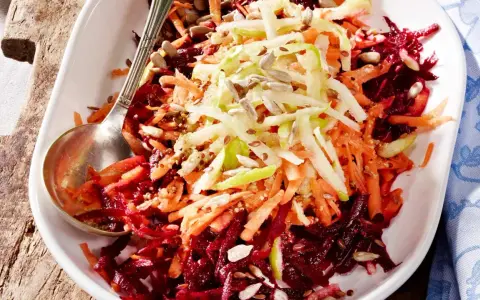 Bunter Salat aus geriebener roter Bete, Karotten und Apfelstiften, garniert mit Sonnenblumenkernen.