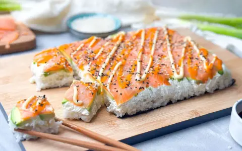 Rechteckiges Sushi mit Lachs und Avocado, verziert mit Mayonnaise und Sesam. Perfekt, um Sushi selber machen zu lernen!