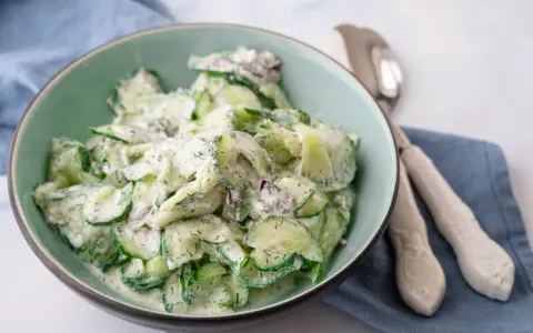 Frischer gurkensalat mit saurer sahne und Dill, garniert mit roten Zwiebeln, in einer Schüssel serviert.