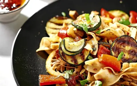 Ein bunter Nudelsalat mit gegrilltem Gemüse, Tomaten und Kräutern. Dazu passen Oliven perfekt.