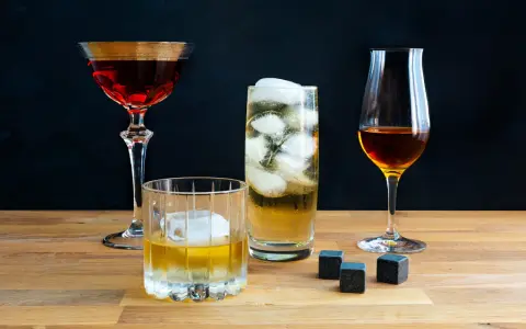 Vier Gläser mit verschiedenen Getränken, darunter ein Whisky-Cocktail, ein Highball und ein Nosing-Glas. So trinkt man Whisky: pur, mit Eis oder als Mixgetränk.