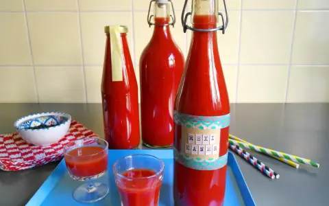 Rot gefüllte Flaschen mit dem Aufdruck "Mexikaner Rezept" und kleine Gläser mit dem Getränk.