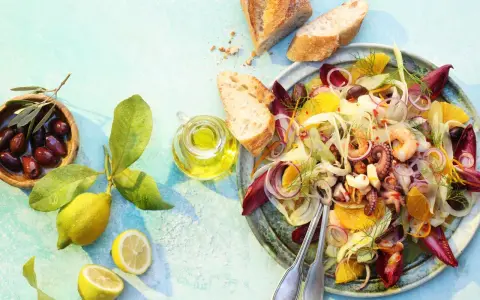 Raffinierte Sommersalate: Ein bunter Meeresfrüchtesalat mit Fenchel, Orange und Oliven, serviert mit Brot und Zitrone.