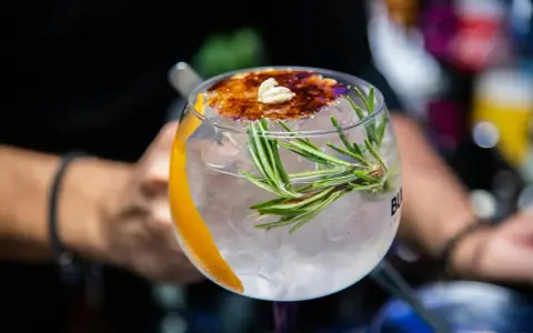 Ein erfrischender Gin Tonic mit Rosmarin und karamellisierter Orangenscheibe. Perfekt für einfache Gin Rezepte.
