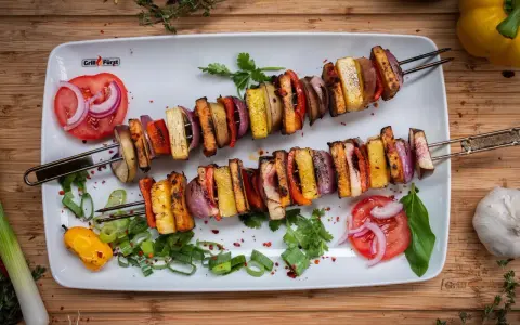 Zwei Spieße mit gegrilltem Gemüse und Tofu, perfekt für ausgefallene Grillrezepte. Bunt und lecker!