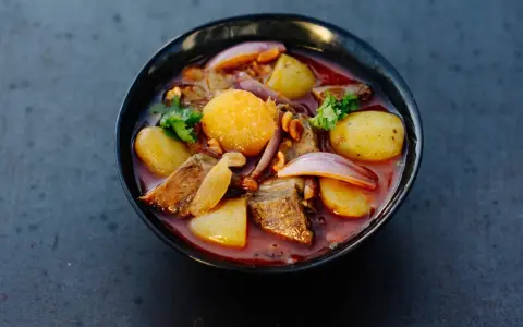 Schüssel mit Massaman Curry, Kartoffeln, Fleisch, Zwiebeln und Koriander.