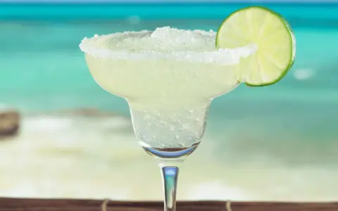 Erfrischende Margarita mit Salzrand und Limettenscheibe, perfekt für ein Strand-Margarita-Rezept.