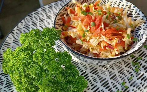 Frischer Chinakohlsalat mit Honig-Senf Dressing, garniert mit Lachs und Schnittlauch. Daneben ein Bund glatte Petersilie.