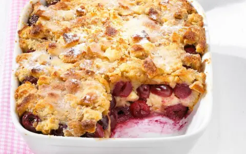 Omas Kirschenmichel Rezept: Ein goldbrauner Auflauf mit saftigen Kirschen und knuspriger Streuselhaube, bestäubt mit Puderzucker.