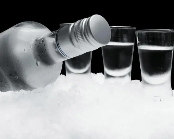 Eiskalte Flasche Wodka und drei Shotgläser auf Eis. So schmeckt Wodka am besten: rein und erfrischend.