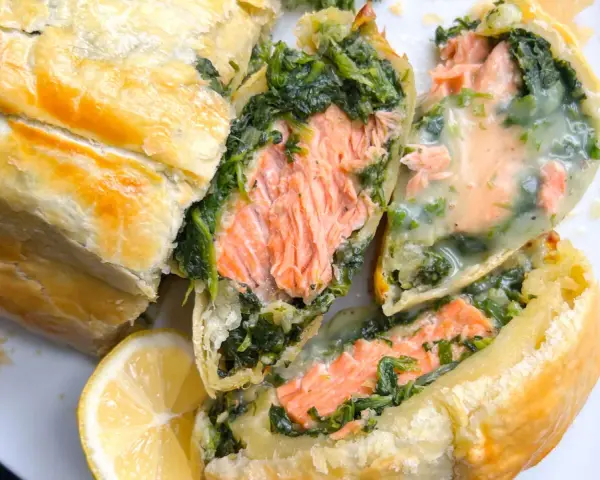 Saftiger Lachs mit Spinat in Blätterteig, ein köstliches Gericht für Fisch-Rezepte. Dazu eine Zitronenspalte.