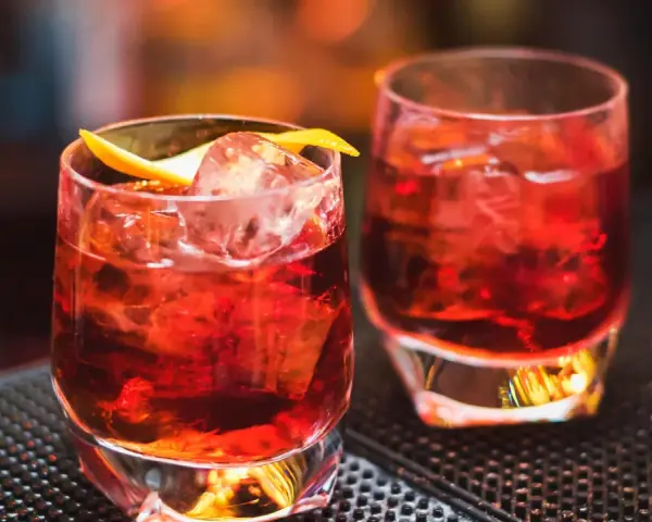 Zwei klassische Negroni-Cocktails mit Eis und Orangenzeste. Das perfekte Rezept für einen originalen Negroni.