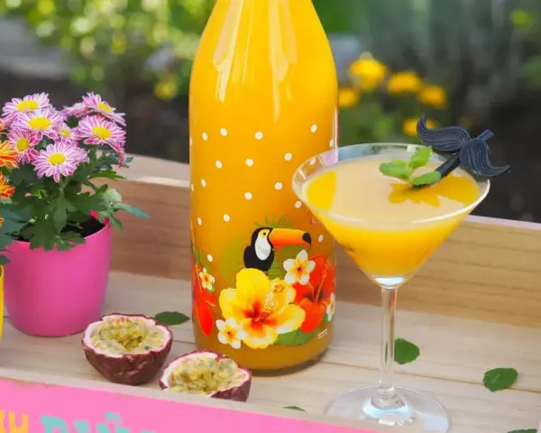 Ein tropischer Solero Cocktail mit Passionsfrucht, Blumen und einem lustigen Schnurrbart-Garnitur.