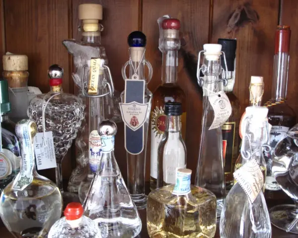 Regal voller Grappa-Flaschen, einige mit Etiketten, die den **Grappa Prozent** angeben.
