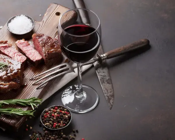 Ein saftiges Steak, perfekt zubereitet, mit einem Glas Rotwein. Was ist Malbec? Ein vollmundiger Wein, der dieses Gericht abrundet.