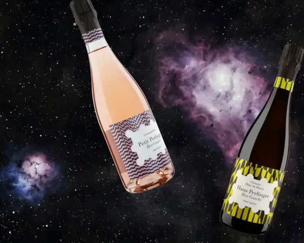 Zwei Flaschen Crémant, eine Rosé, eine Blanc de Blancs, schweben im Sternenhimmel. Was ist Crémant? Ein prickelnder Genuss!