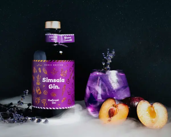 Ein magischer lila Gin Tonic mit Pflaume und Lavendel, daneben eine Flasche Sîmsala Gin.