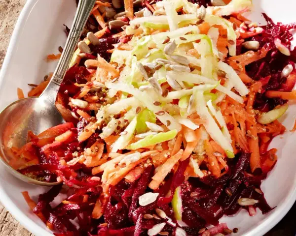Bunter Salat aus geriebener roter Bete, Karotten und Apfelstiften, garniert mit Sonnenblumenkernen.