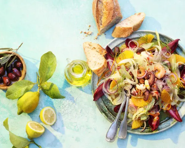 Raffinierte Sommersalate: Ein bunter Meeresfrüchtesalat mit Fenchel, Orange und Oliven, serviert mit Brot und Zitrone.