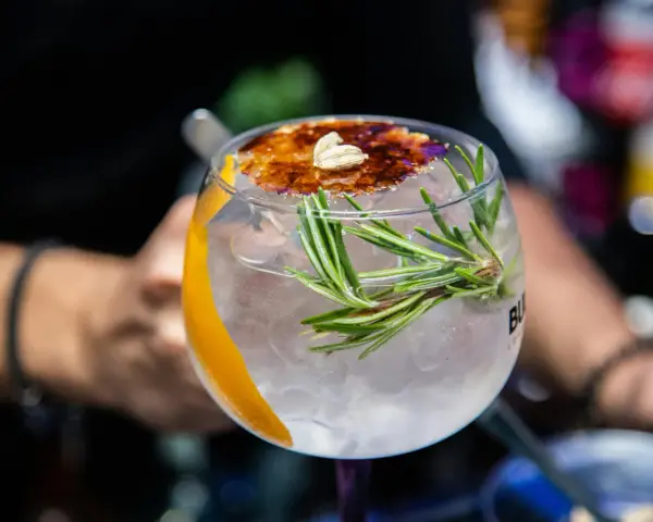 Ein erfrischender Gin Tonic mit Rosmarin und karamellisierter Orangenscheibe. Perfekt für einfache Gin Rezepte.