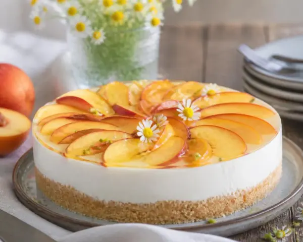 Eine **schnelle Torte** mit Pfirsichscheiben und Götterblümchen auf cremigem Käsekuchenboden.