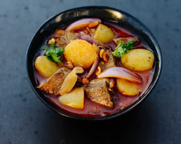 Schüssel mit Massaman Curry, Kartoffeln, Fleisch, Zwiebeln und Koriander.