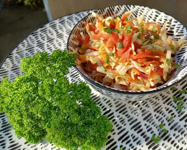 Frischer Chinakohlsalat mit Honig-Senf Dressing, garniert mit Lachs und Schnittlauch. Daneben ein Bund glatte Petersilie.