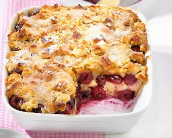 Omas Kirschenmichel Rezept: Ein goldbrauner Auflauf mit saftigen Kirschen und knuspriger Streuselhaube, bestäubt mit Puderzucker.