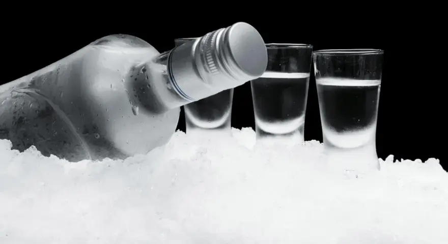 Eiskalte Flasche Wodka und drei Shotgläser auf Eis. So schmeckt Wodka am besten: rein und erfrischend.