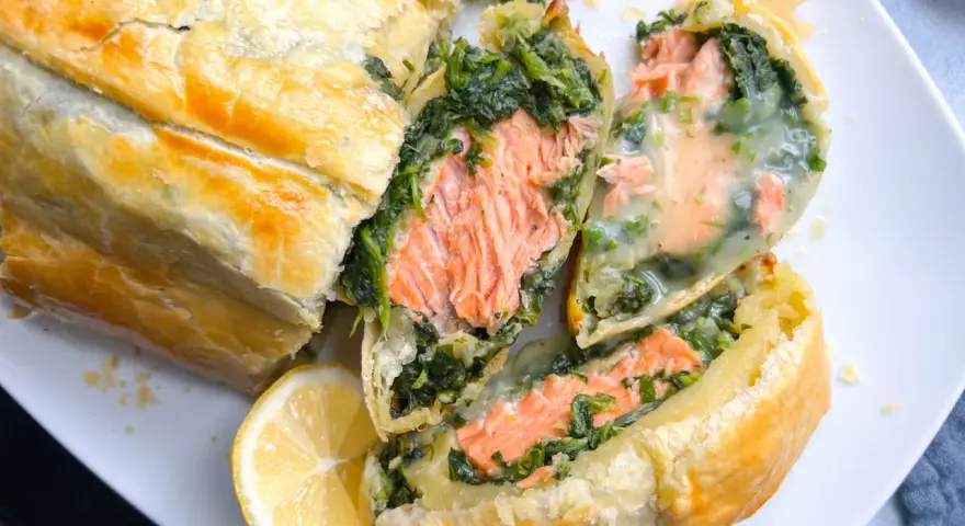 Saftiger Lachs mit Spinat in Blätterteig, ein köstliches Gericht für Fisch-Rezepte. Dazu eine Zitronenspalte.