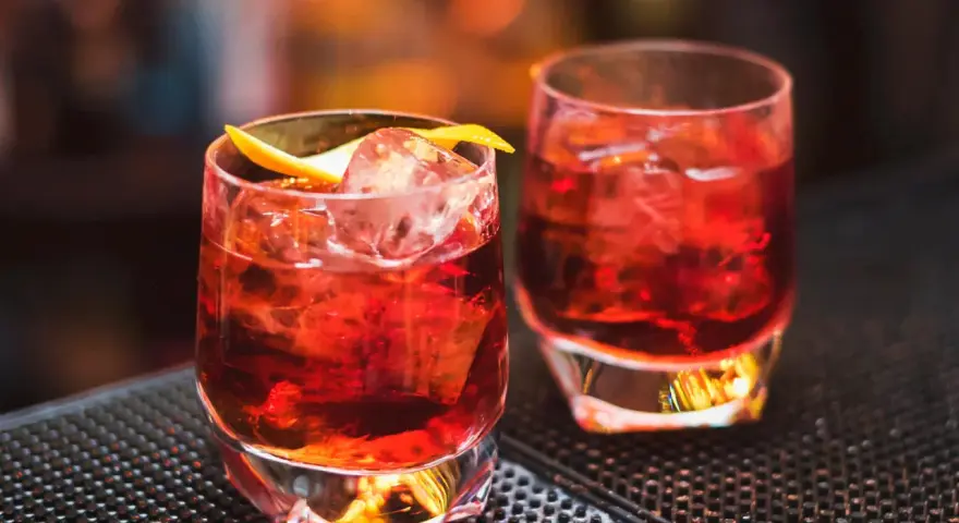 Zwei klassische Negroni-Cocktails mit Eis und Orangenzeste. Das perfekte Rezept für einen originalen Negroni.
