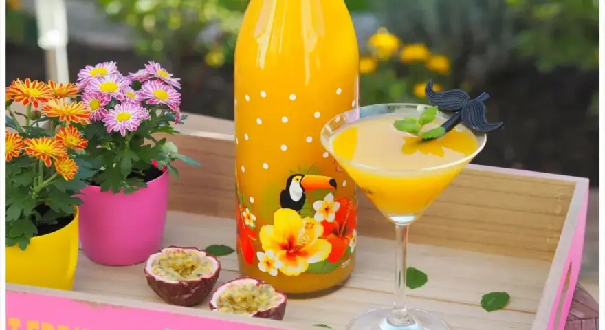 Ein tropischer Solero Cocktail mit Passionsfrucht, Blumen und einem lustigen Schnurrbart-Garnitur.