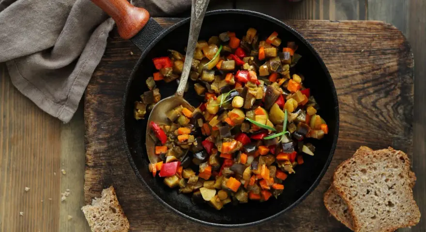 Ratatouille rezept: Buntes Gemüse aus Aubergine, Paprika und Karotten in einer Pfanne, serviert mit Brot.
