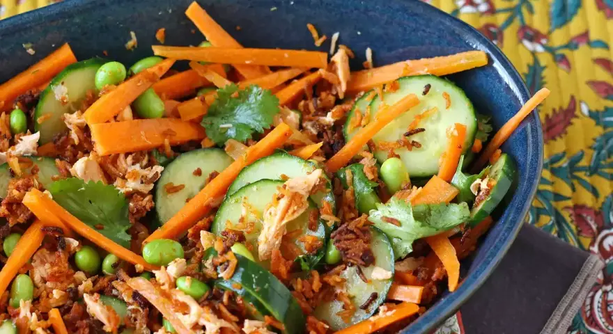 Herzhafte Salate mit Karottenstreifen, Gurkenscheiben, Edamame und zerrupftem Lachs. Knusprige Röstzwiebeln sorgen für Textur.