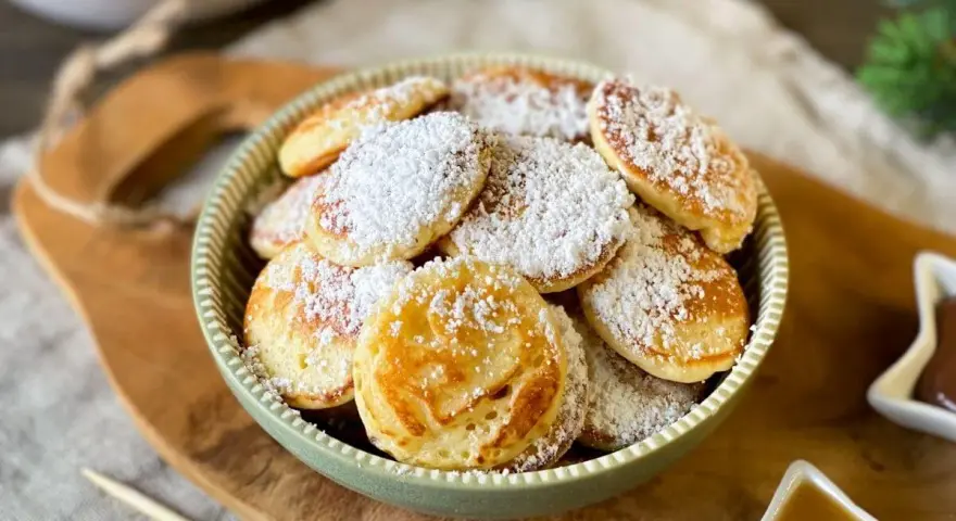 Köstliche Poffertjes, bestäubt mit Puderzucker, warten auf das Poffertjes Rezept. Ein süßer Genuss!