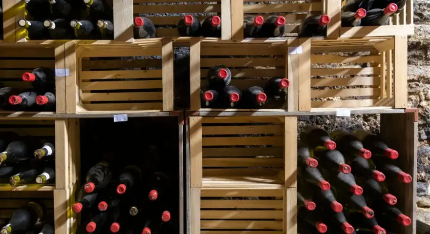 Holzregale mit vielen Flaschen Wein, die perfekt zum Wein lagern bereitstehen.