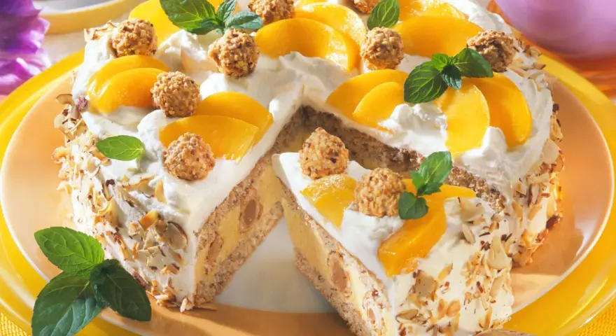 Eine köstliche Giotto Torte mit Pfirsichspalten, Sahne und gehackten Mandeln. Kleine Pralinen und Minzblätter zieren die Torte.