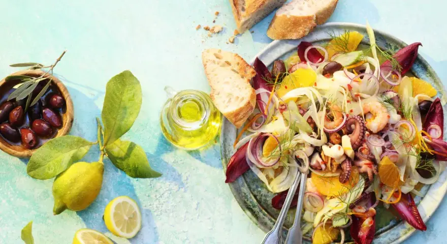Raffinierte Sommersalate: Ein bunter Meeresfrüchtesalat mit Fenchel, Orange und Oliven, serviert mit Brot und Zitrone.