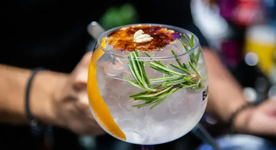 Ein erfrischender Gin Tonic mit Rosmarin und karamellisierter Orangenscheibe. Perfekt für einfache Gin Rezepte.